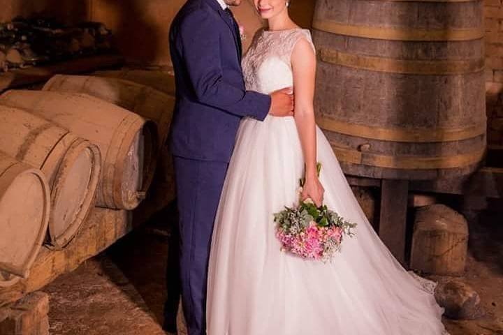 Casal fotografado entre grandes barris de madeira